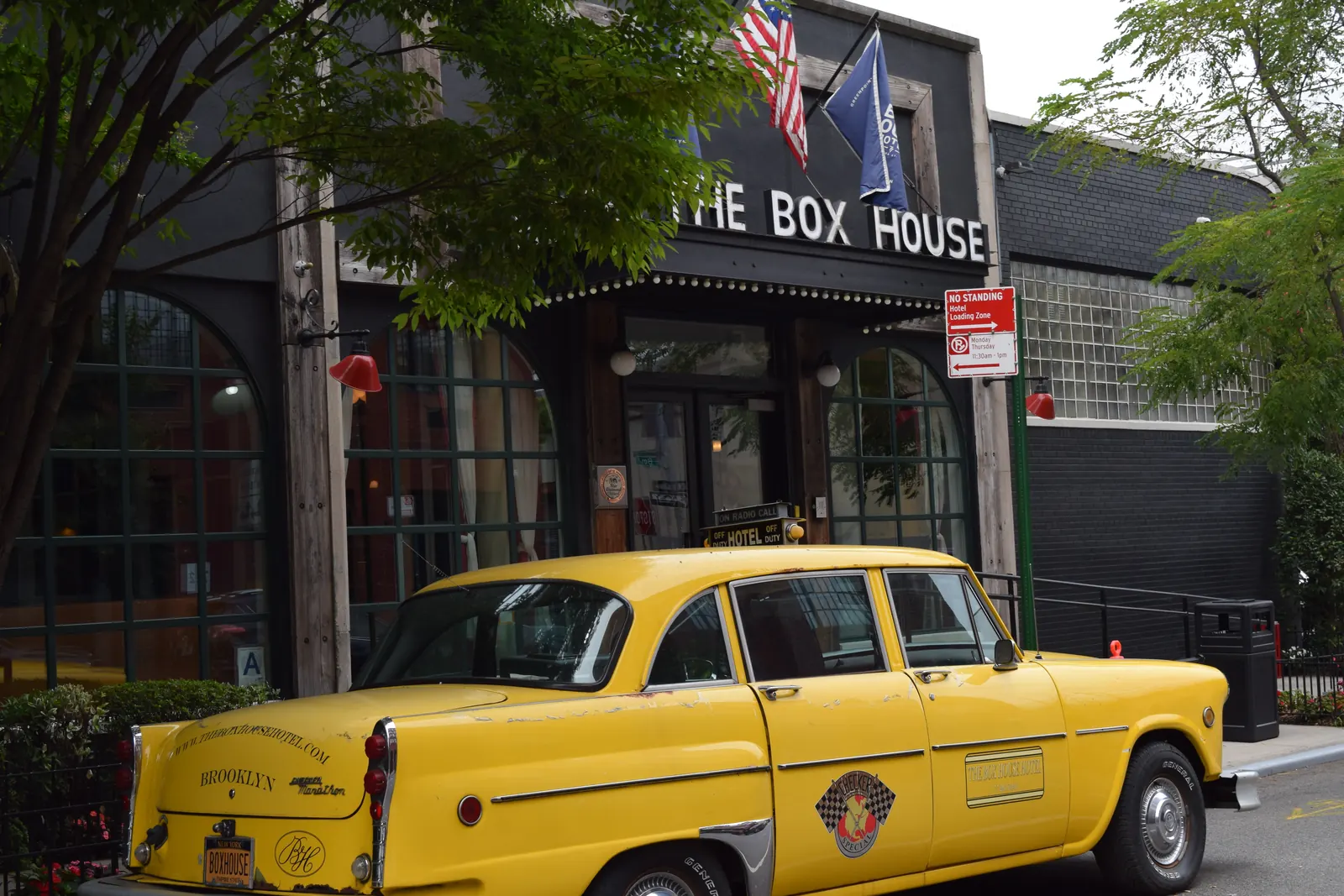 The Box House Hotel entrance at 77 Box Street in Greenpoint, Brooklyn, with the hotel vintage yellow Checker cab parked out front