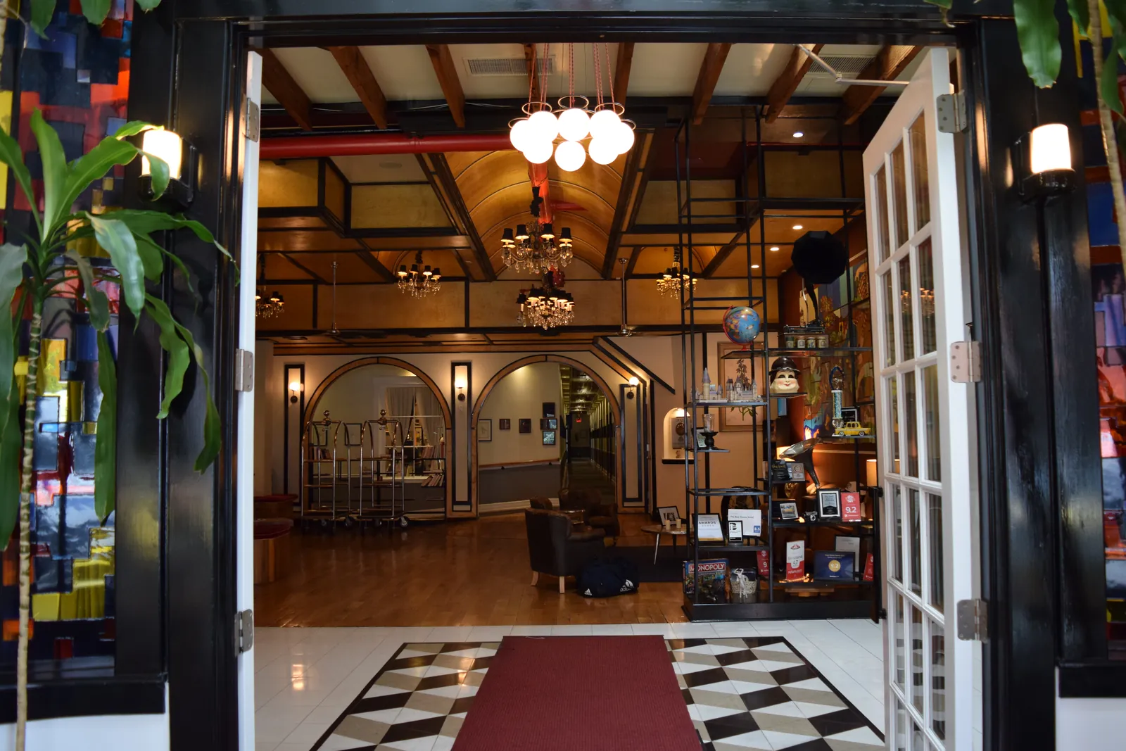 The lobby of The Box House Hotel in Greenpoint, Brooklyn, seen through open glass doors onto a checkerboard floor